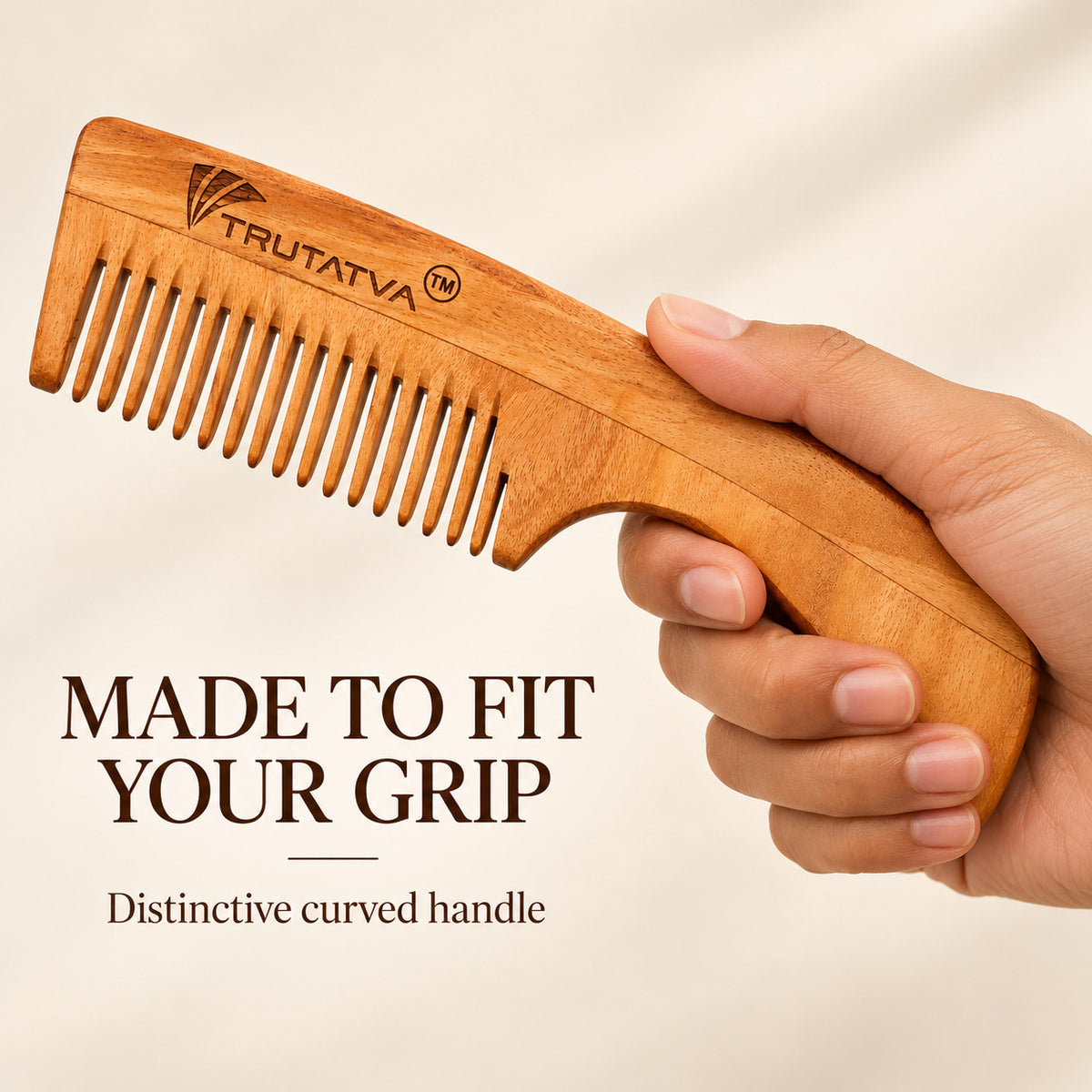 Trutatva Neem wood comb with distinctive curved handle held in hand
